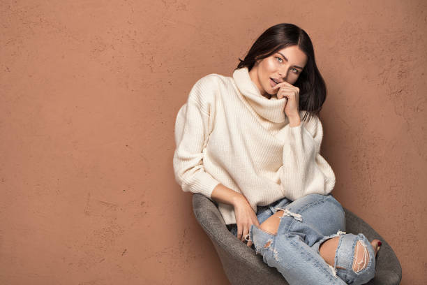 Fashionable beautiful woman in warm sweater posing, looking at camera.